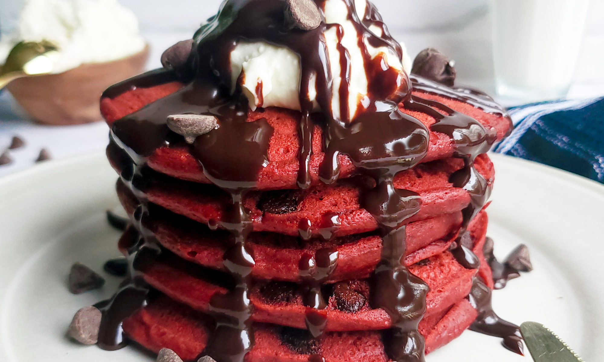 Stack of red velvet pancakes with cream cheese topping