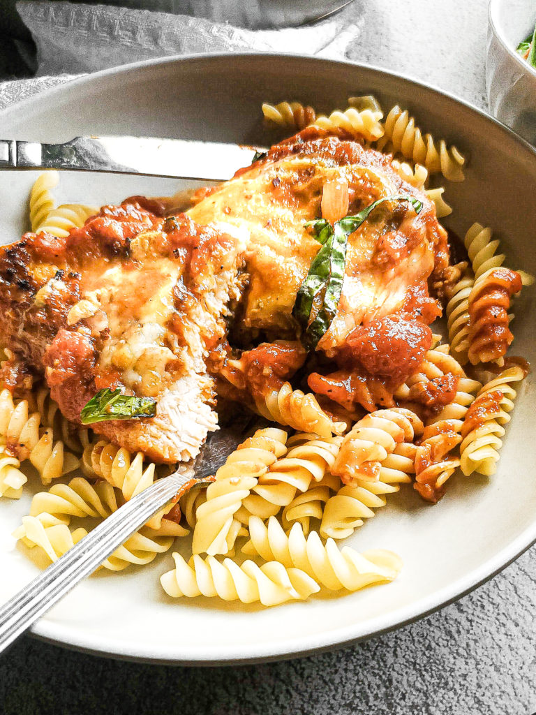 Piece of chicken parmesan in a bowl with pasta